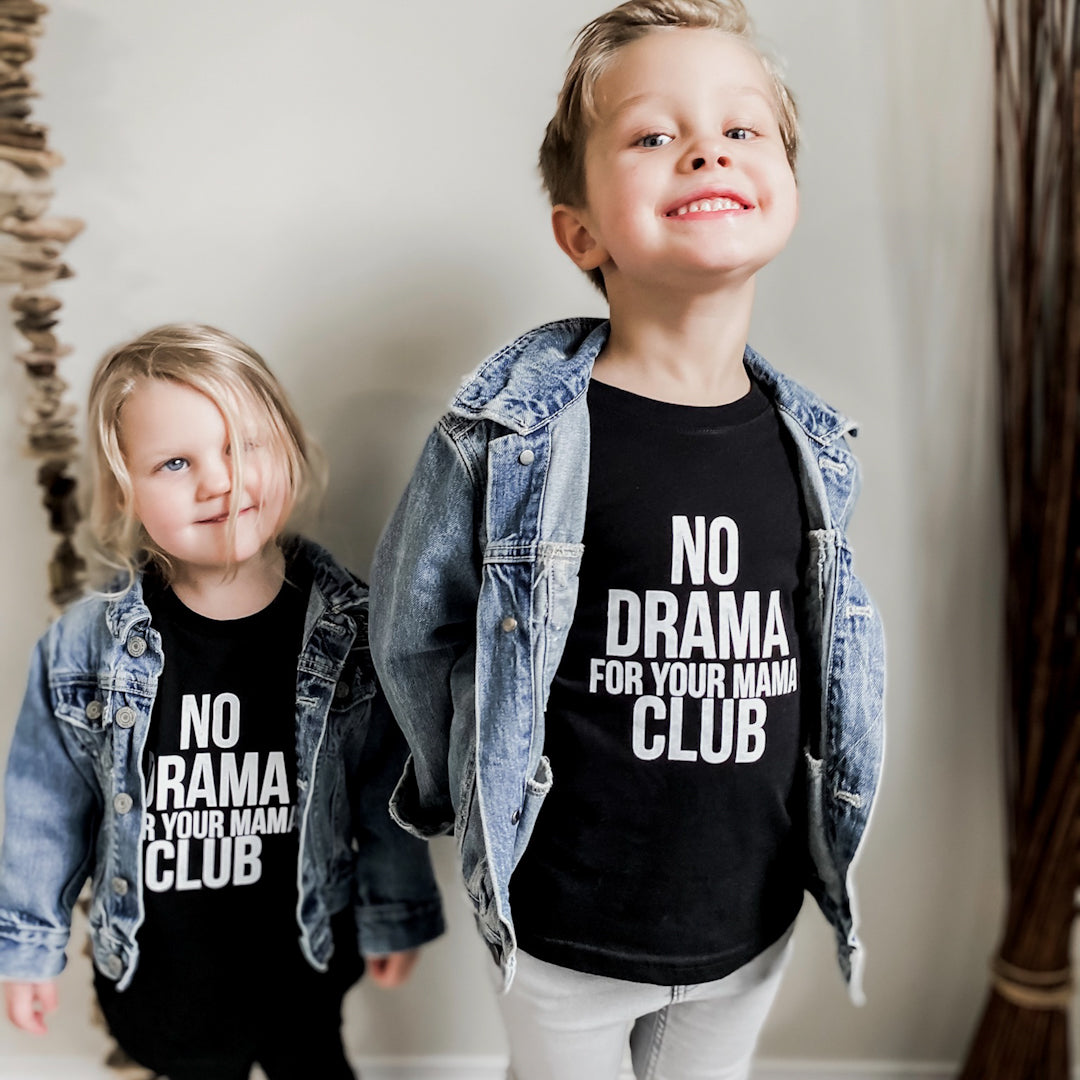 Two year old girl and 4 year old boy wearing matching no drama for your mama club long sleeved shirts in black and blue denim jackets. Girl is wearing black leggings and boy is wearing light grey jeans.