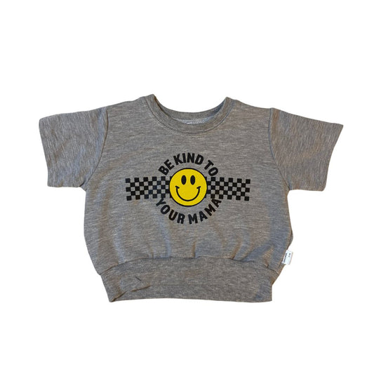 Short sleeved retro fit baby and toddler sweatshirt in heather grey. The front says "be kind to your mama" in black around a yellow smiley face and a checkerboard racing stripe.