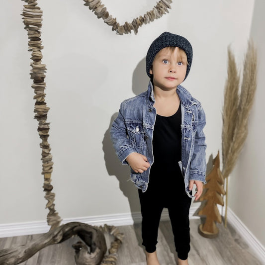 Four year old boy wearing the romper in black , denim jacket, and a blue toque.