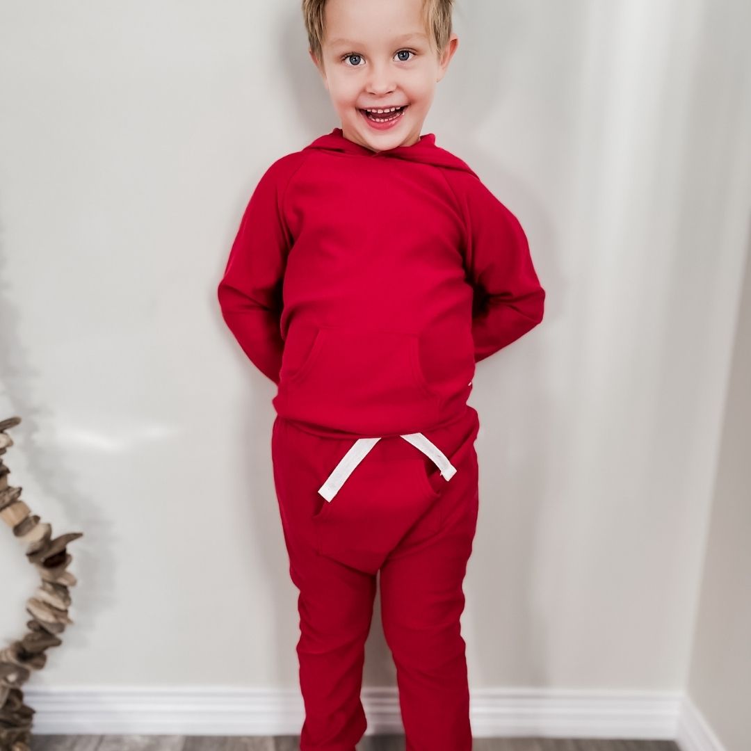 little boy wearing the harem pants in red with the front pocket and the matching hooded raglan pullover sweater.