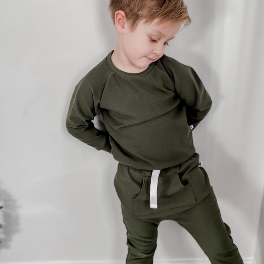 boy wearing the raglan pullover in forest green and the matching harem pants.