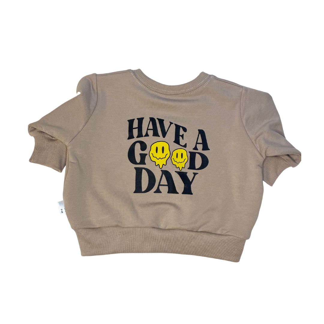 Front of the "Have a Good Day" sweatshirt in a natural fawn color featuring "have a good day with two drippy smiley faces instead of o's.