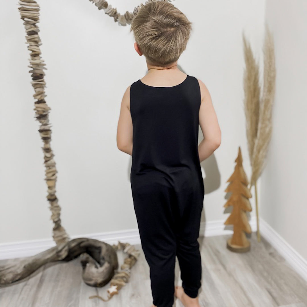 Little boy showing off the back of the black romper.