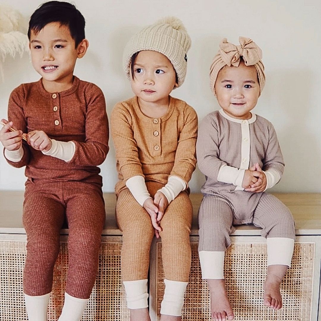 Three siblings sitting on bench wearing the waffle sets in cocoa and caramel and the romper in taupe
