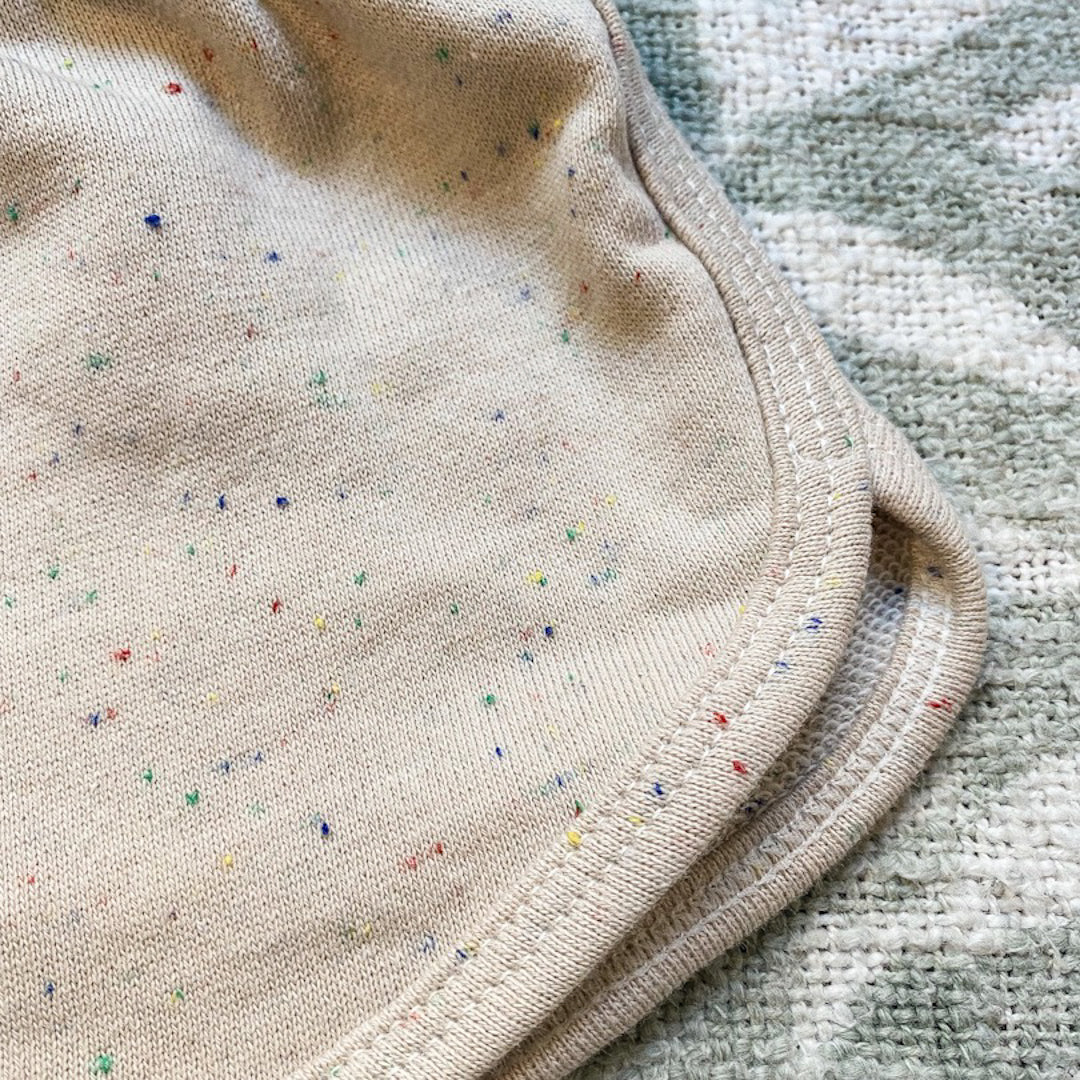 Close up of the French Terry track shorts in speckled beige showing the weave and the multicoloured tiny sprinkle speckles in the beige fabric.