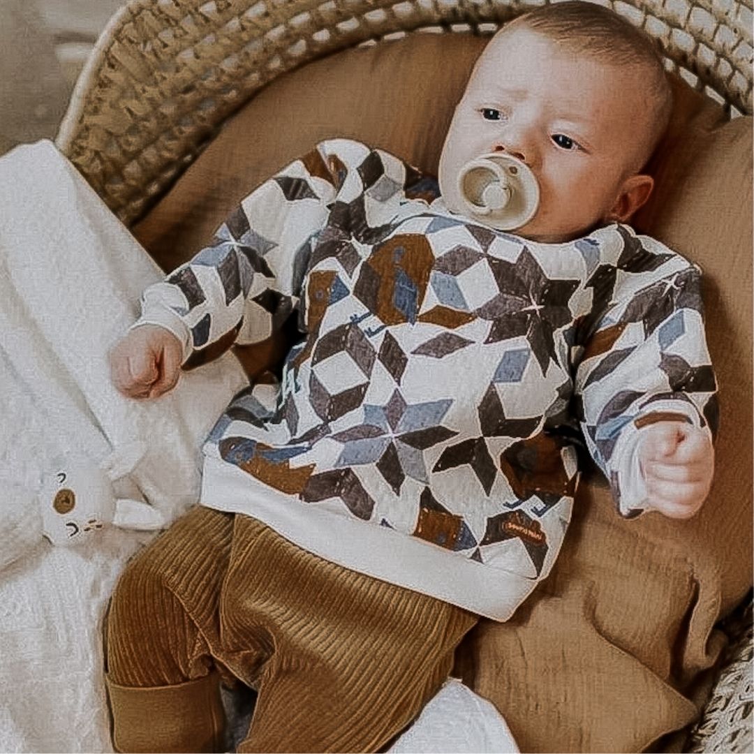 Baby boy in quilted pullover in desert breeze.