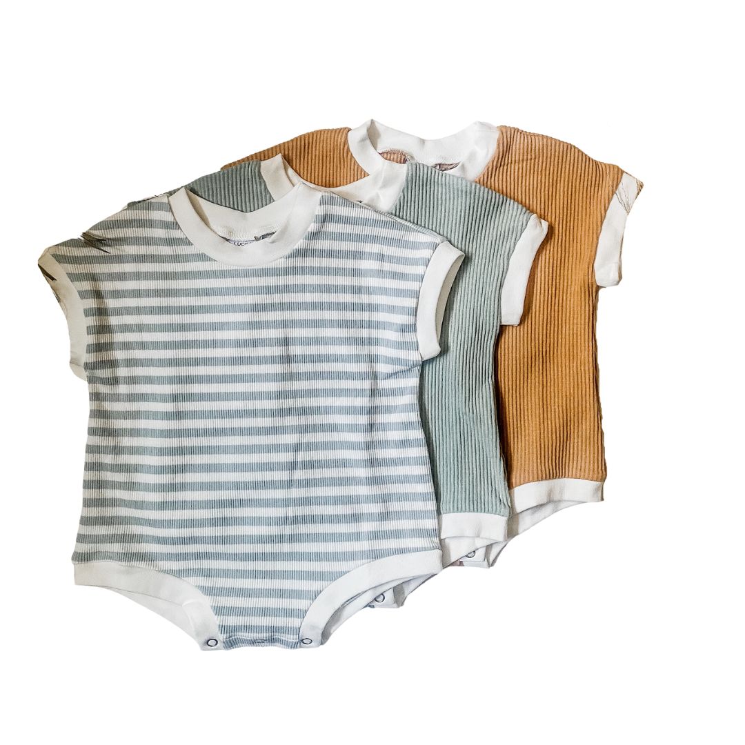 Short sleeved ribbed bubble rompers in waves, sand, and ocean.