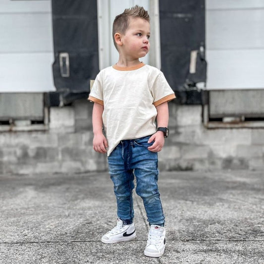 Little boy wearing the slim fit denim joggers and a cream shirt