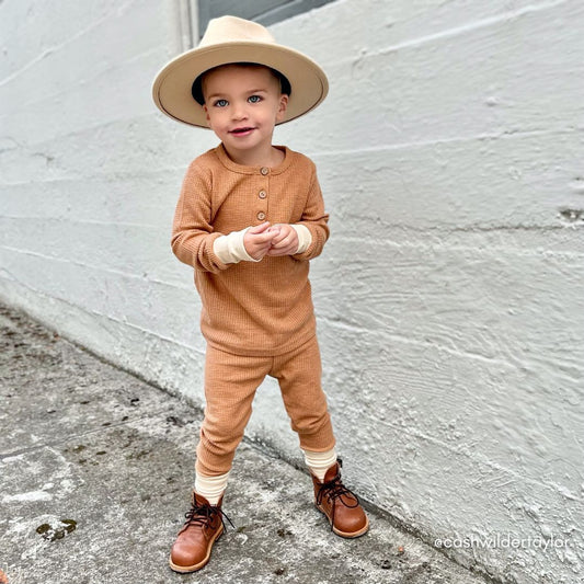 toddler boy in a boho California styling of the waffle set in caramel, cream hat, and matching boots.