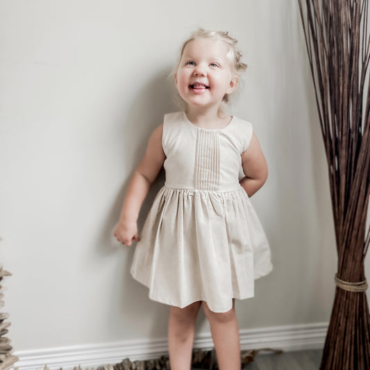 blond girl smiling wearing the pintuck dress in cream.