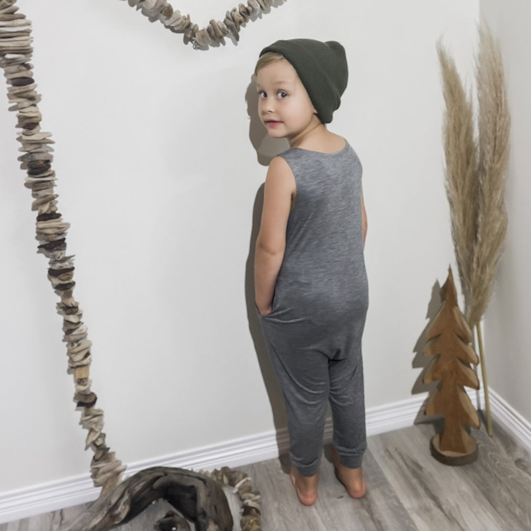 Little boy showing off the back of the romper in heather grey.