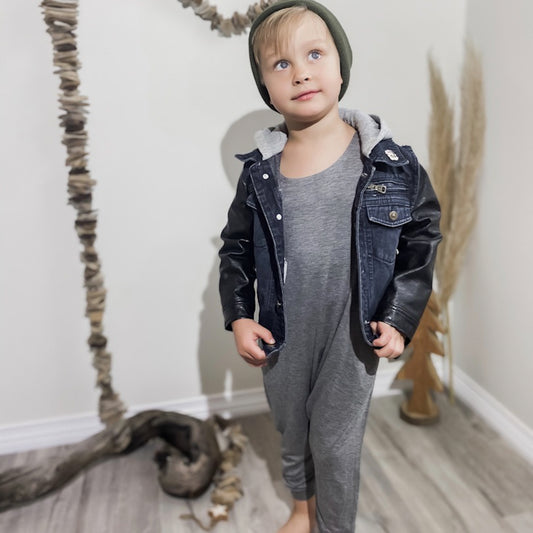 four year old boy looking above the camera wearing the romper in heather grey , dark denim jacket, and a green toque.