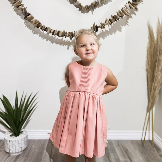 blonde girl smiling wearing the pintuck dress in French pink.